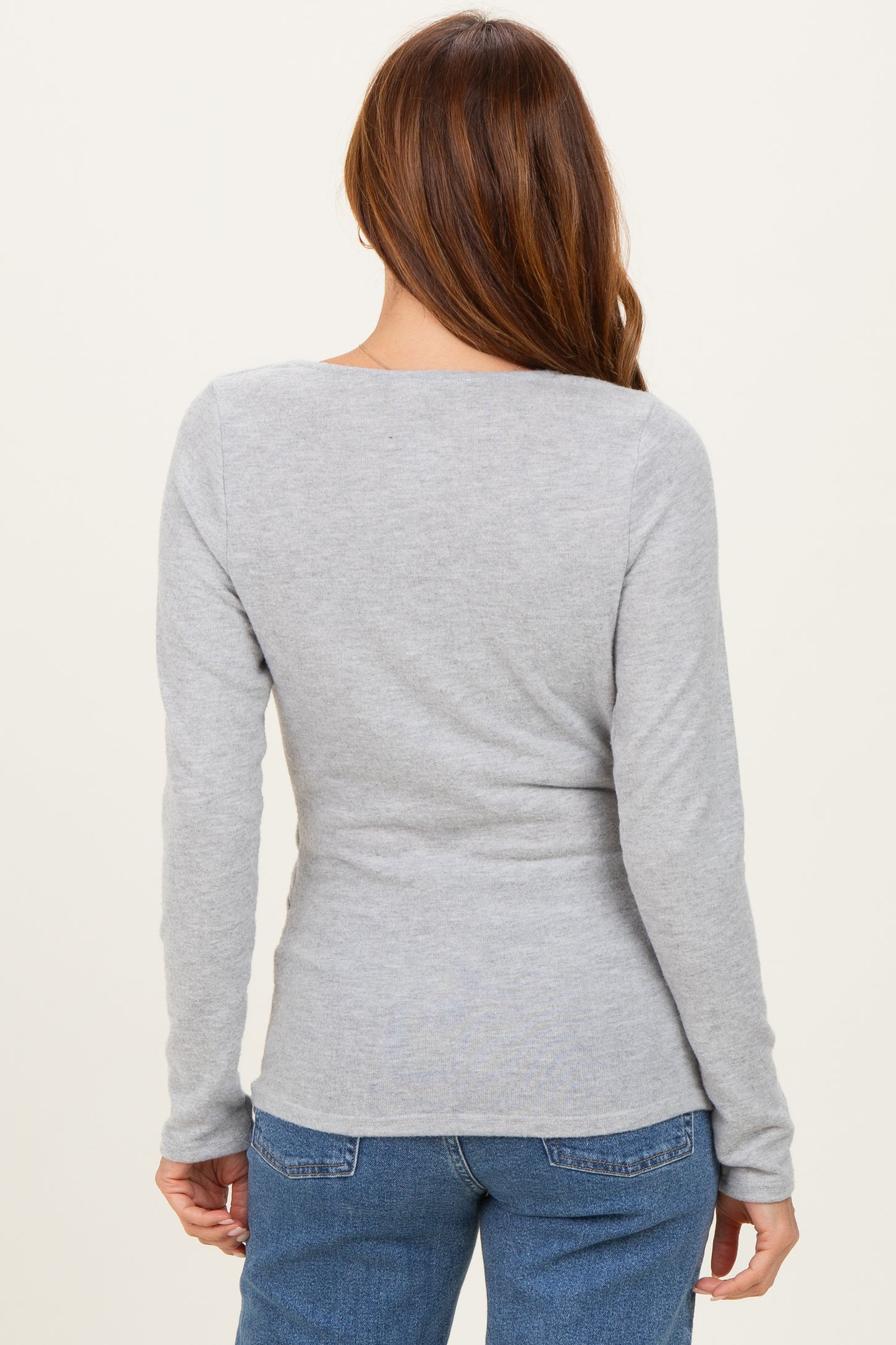 woman wearing a fitted grey long sleeve top, showing the back view with a scoop neckline and soft fabric