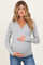 woman wearing a gray long sleeve maternity top and holding her baby bump