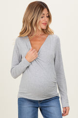 woman wearing a gray long sleeve maternity top and showcasing her baby bump