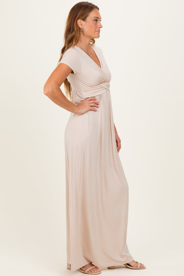 woman wearing a light beige short sleeve maxi dress with a knot detail at the waist