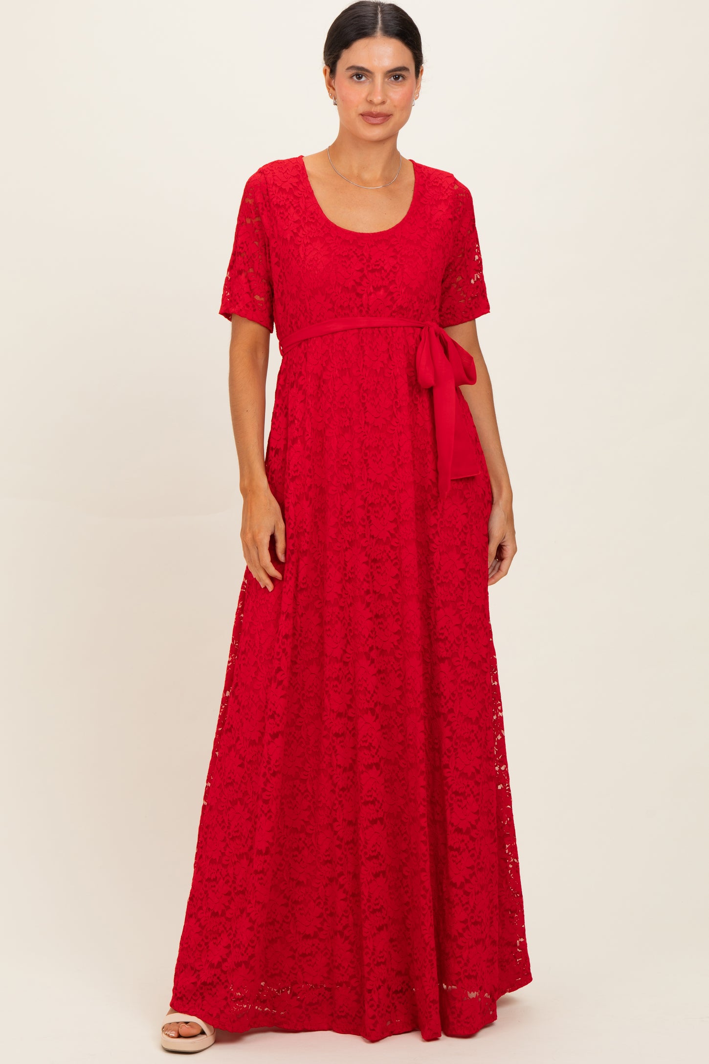 woman wearing a red lace maxi dress with a scoop neckline and a tie waist detail