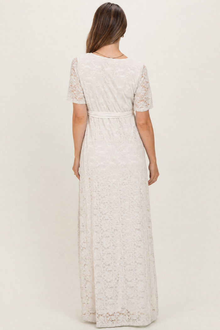 woman wearing a cream lace maternity dress with short sleeves and a tie waist, photographed from the back