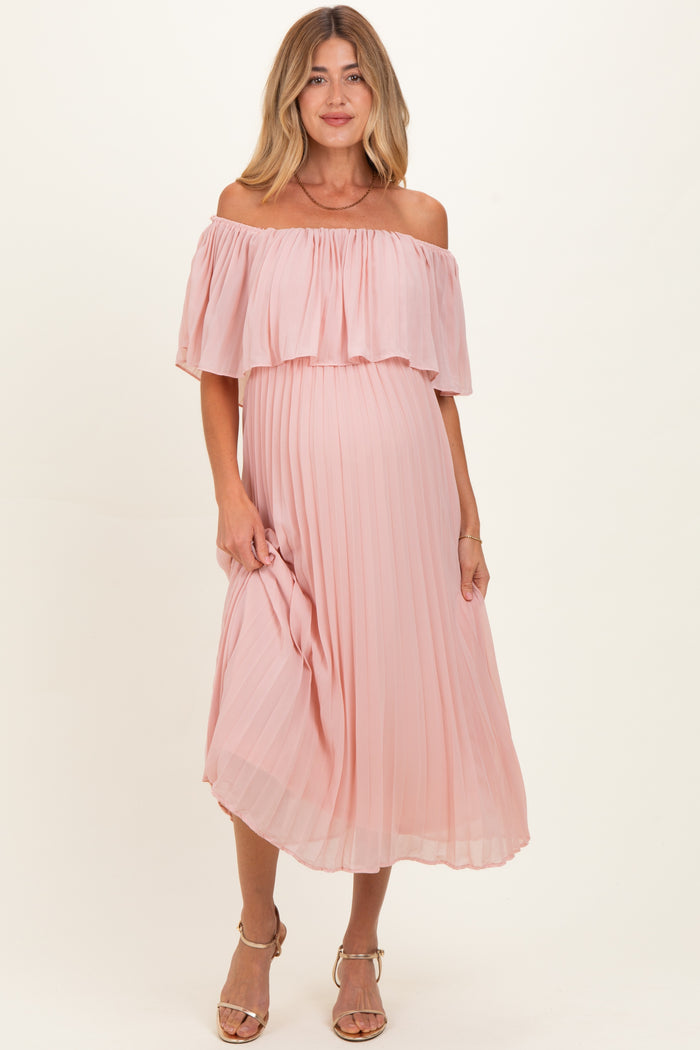 woman wearing a blush pink off-the-shoulder pleated maternity dress with a visible baby bump
