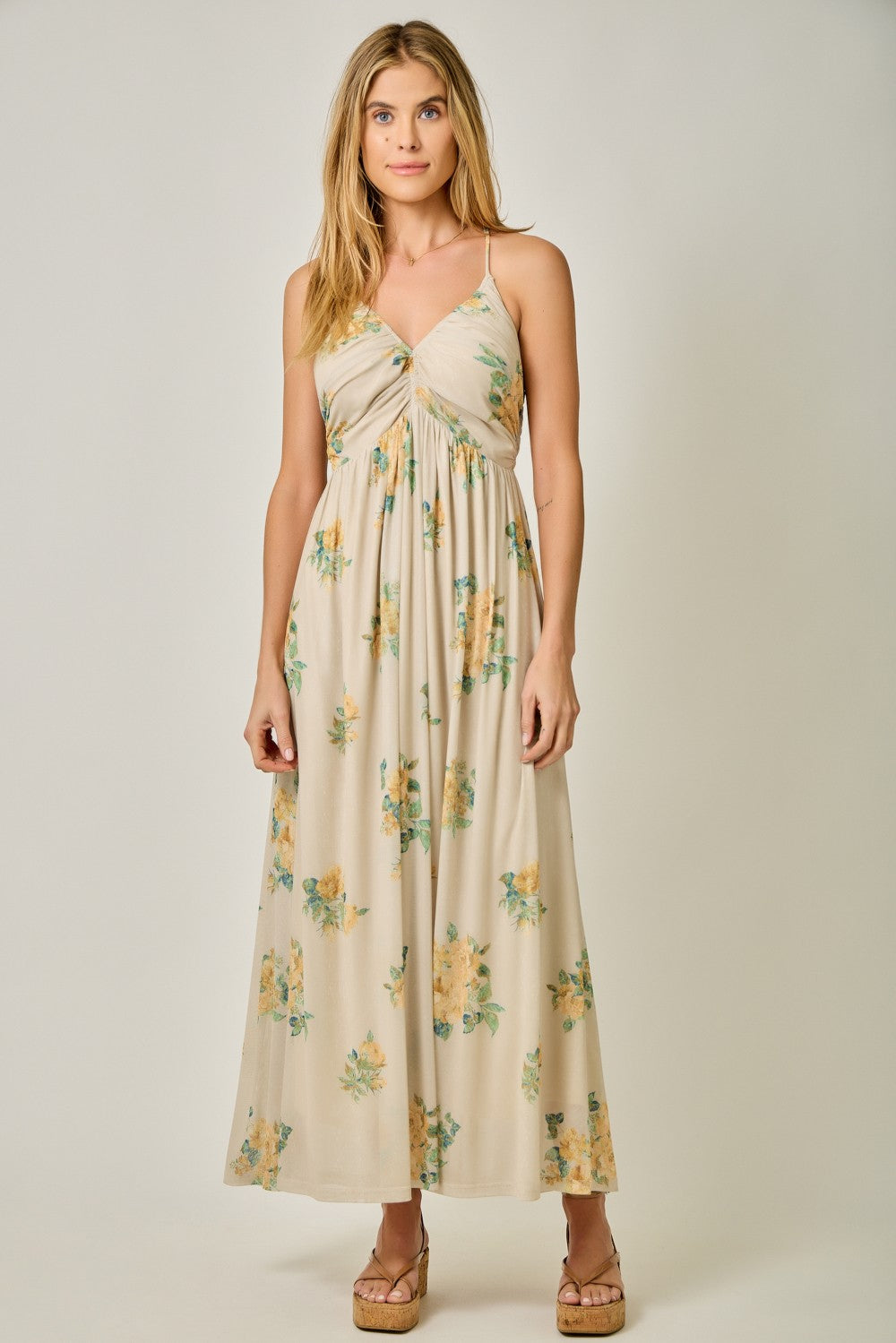 woman wearing a floral print beige maxi dress with a twisted front detail and adjustable spaghetti straps