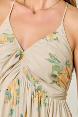 woman wearing a beige floral print maxi dress with adjustable spaghetti straps and ruched detail on the bodice