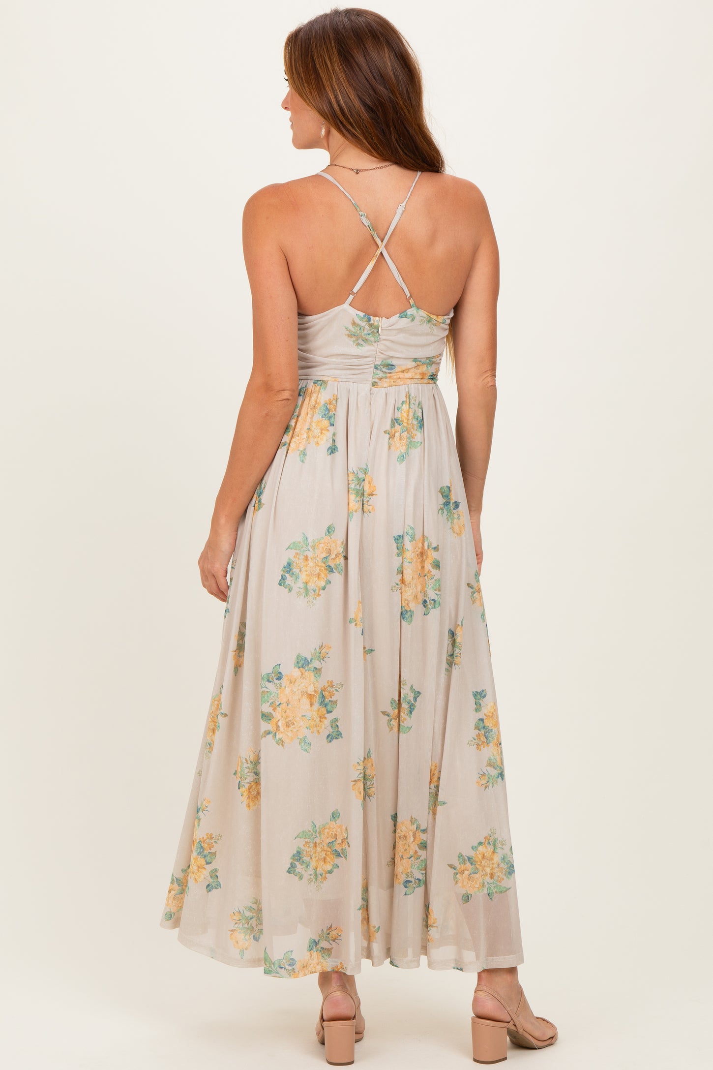 woman wearing a floral print maxi dress with crisscross back straps and flowy skirt
