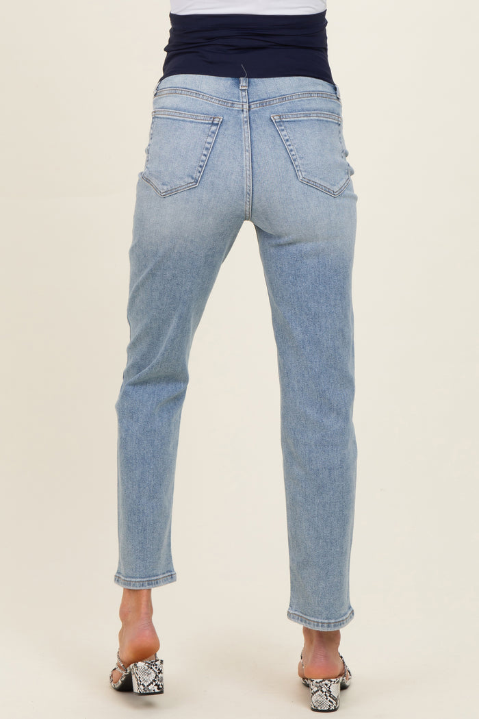 woman wearing light blue maternity jeans, seen from the back, styled with a black top and heeled sandals
