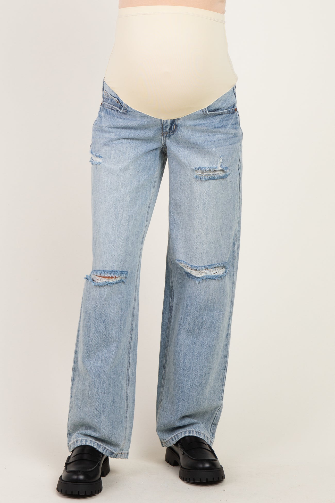 woman wearing distressed light blue maternity jeans with a beige over-the-bump waistband and a visible baby bump