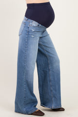 woman wearing light blue wide-leg maternity jeans with a dark blue over-the-bump waistband and visible baby bump