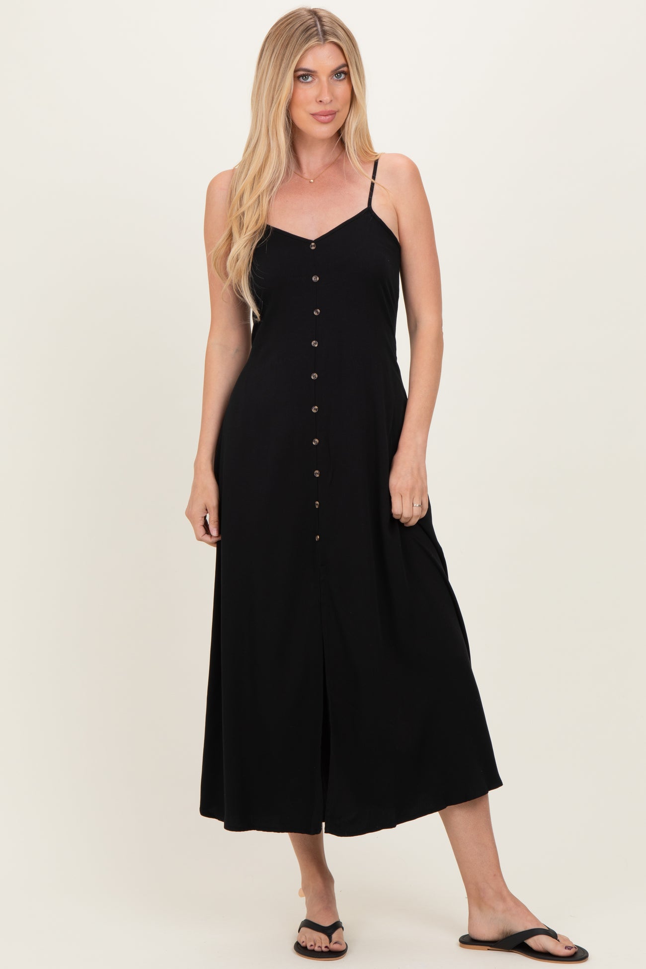woman wearing a black button-up midi dress with adjustable straps and a flowy fit