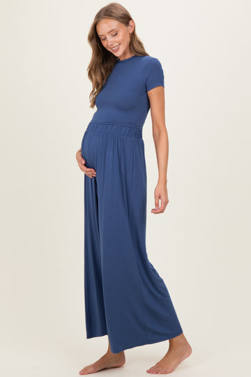 woman wearing a navy blue maternity jumpsuit with a fitted top and wide-leg pants, showing her baby bump