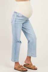 woman wearing light blue maternity jeans with a distressed knee and a beige belly panel, showing her baby bump
