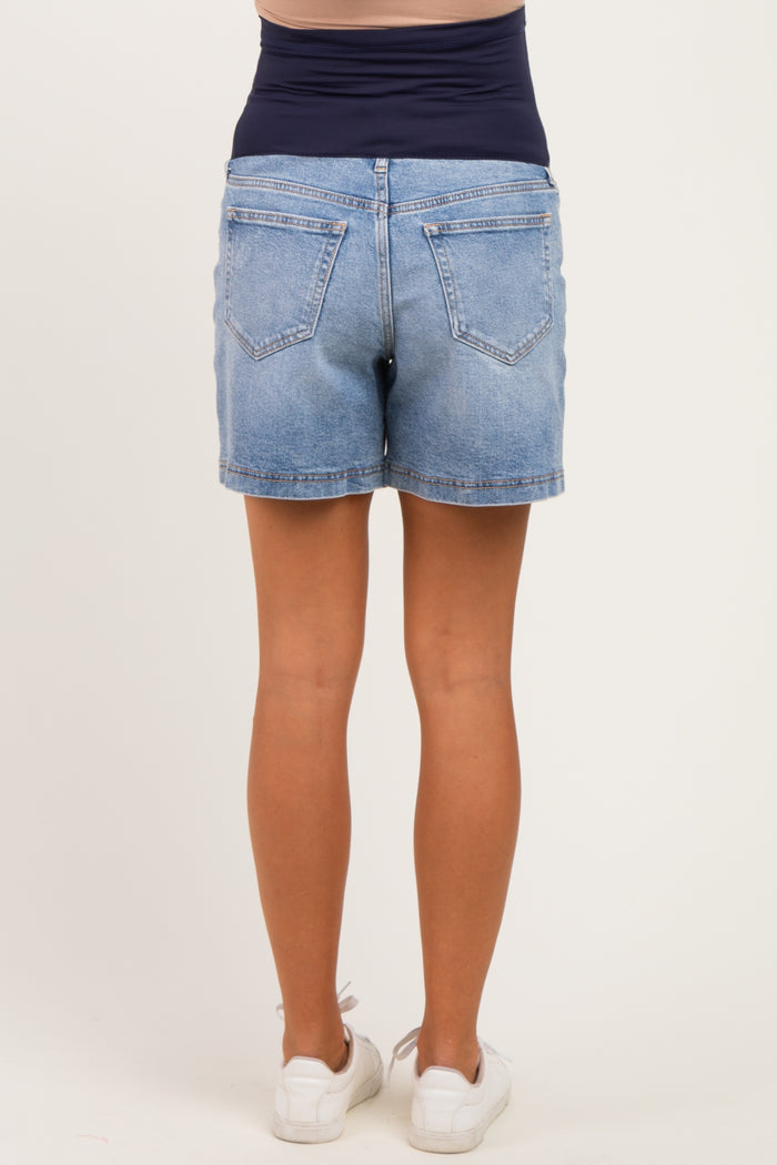 woman wearing light wash maternity shorts with a stretchy navy waistband, viewed from the back