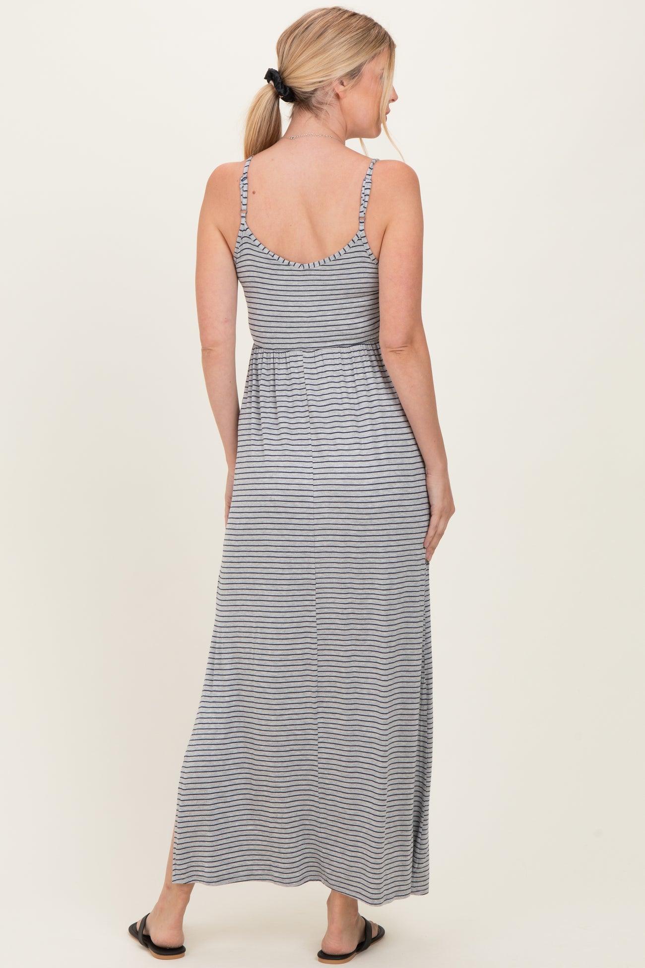 woman wearing a striped grey maxi dress with a fitted bodice and flared skirt, shown from the back