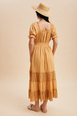 woman wearing a mustard yellow maxi dress with lace detailing and puff sleeves, styled with a straw hat