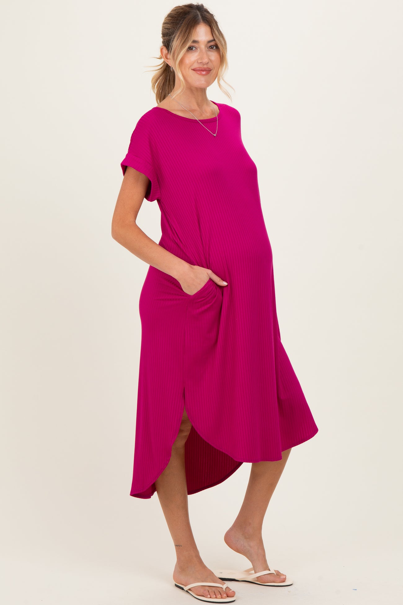 woman wearing a bright pink short sleeve maternity dress with pockets and asymmetric hemline