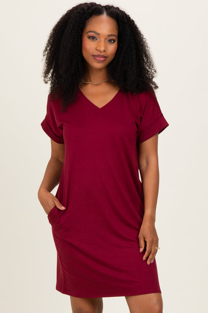 woman wearing a burgundy v-neck short sleeve dress with pockets and rolled cuffs
