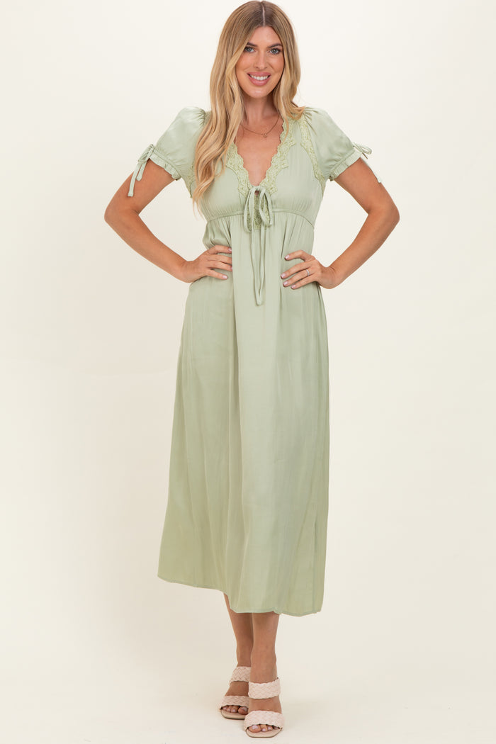 woman wearing a light green midi dress with short sleeves, lace detailing, and a tie waist