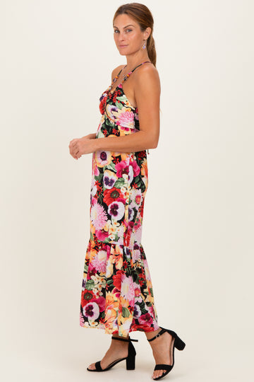 woman wearing a floral maxi dress with spaghetti straps and a ruffled hem, paired with black strappy heels