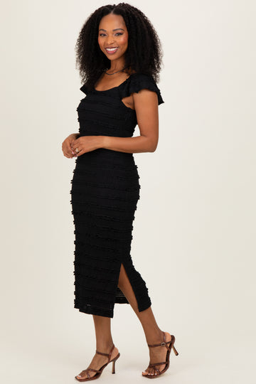 woman wearing a black fitted midi dress with ruffled sleeves and side slits, paired with strappy heels