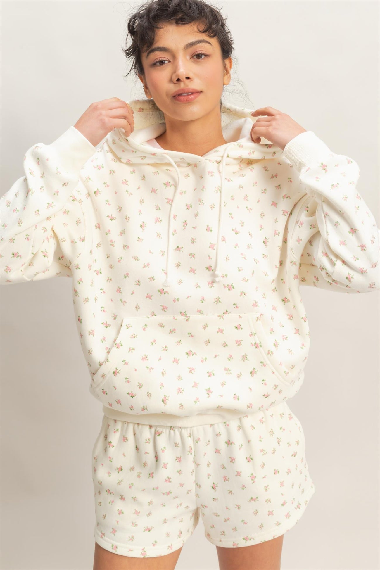 woman wearing a cream floral print hoodie and matching shorts with an elastic waistband