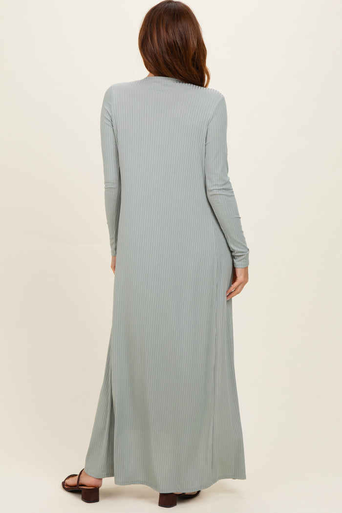 woman wearing a long sage green ribbed maxi dress with long sleeves and side slits