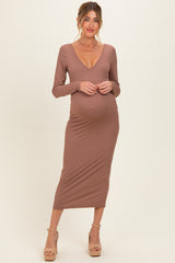 woman wearing a light brown maternity ribbed dress with a deep v-neck and a visible baby bump