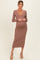 woman wearing a light brown maternity ribbed dress with a deep v-neck and a visible baby bump