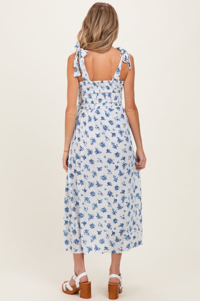 woman wearing a blue and white floral maternity dress with tie straps and a smocked back, showing a baby bump