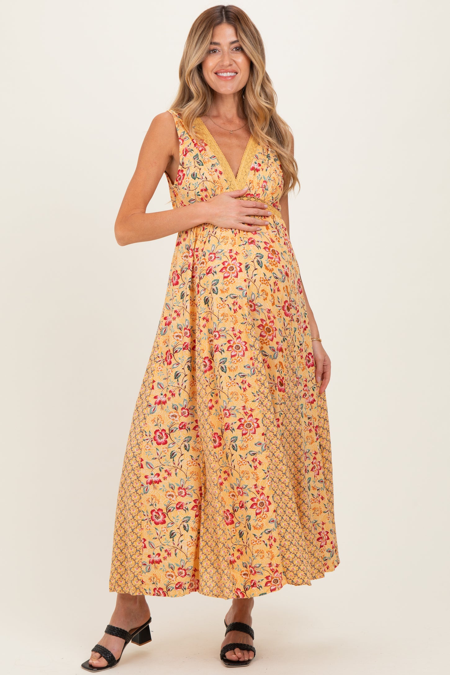 woman wearing a yellow floral maternity dress with a v-neckline and holding her baby bump