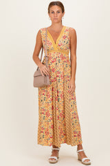 woman wearing a yellow floral maxi dress with a v-neckline and a fitted waist, carrying a small handbag