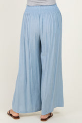 woman wearing light blue wide-leg pants with a smocked waistband, viewed from the back