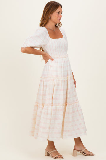 woman wearing a white floral puff sleeve maxi dress with a square neckline and tiered skirt, side profile view