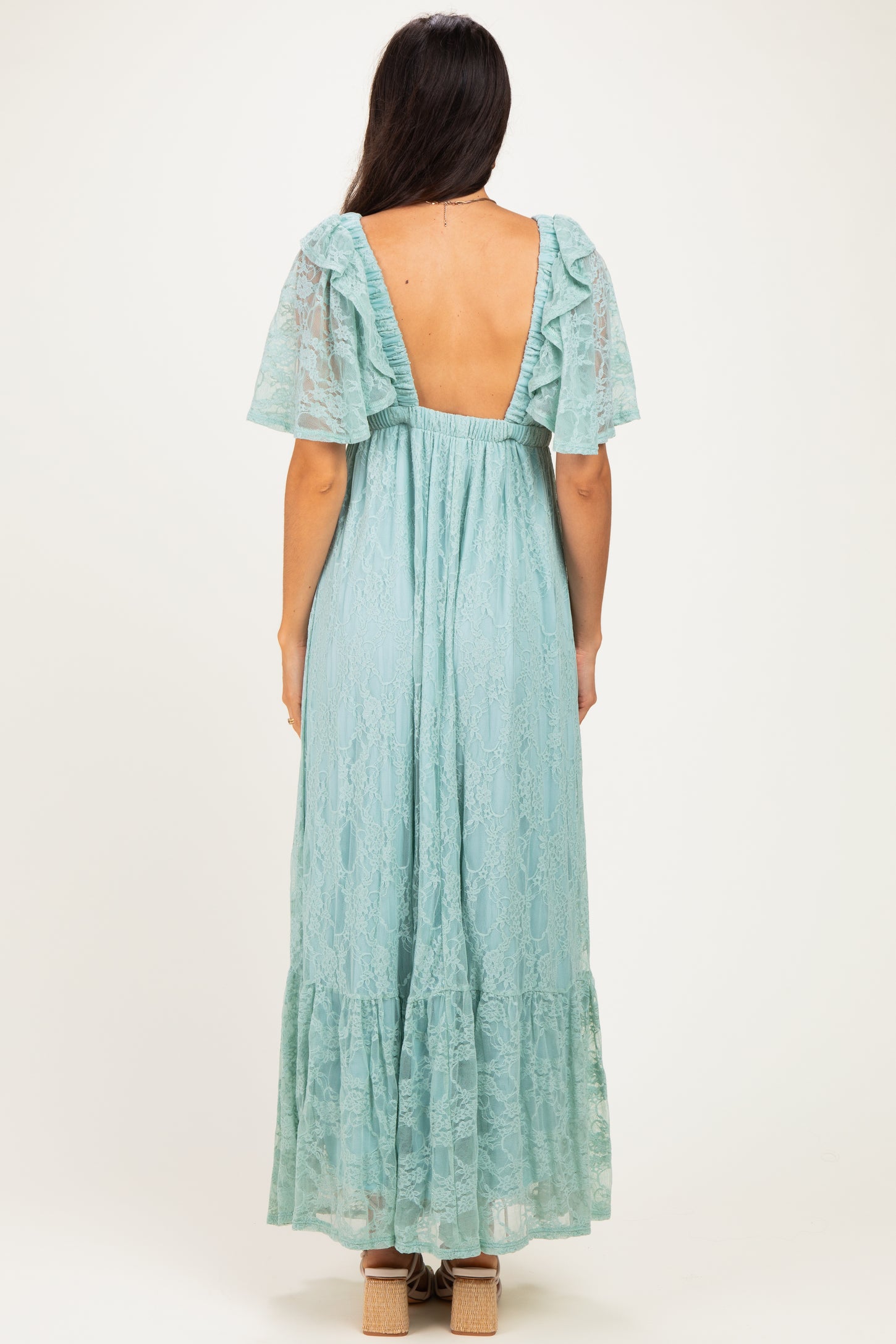 woman wearing a light blue lace maxi dress with ruffled sleeves and a deep back neckline