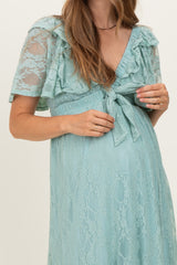 woman wearing a light blue lace maternity dress with short ruffled sleeves and a tie at the waist, showing her baby bump