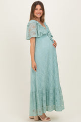 woman wearing a light blue lace maternity maxi dress with ruffle details and holding her baby bump