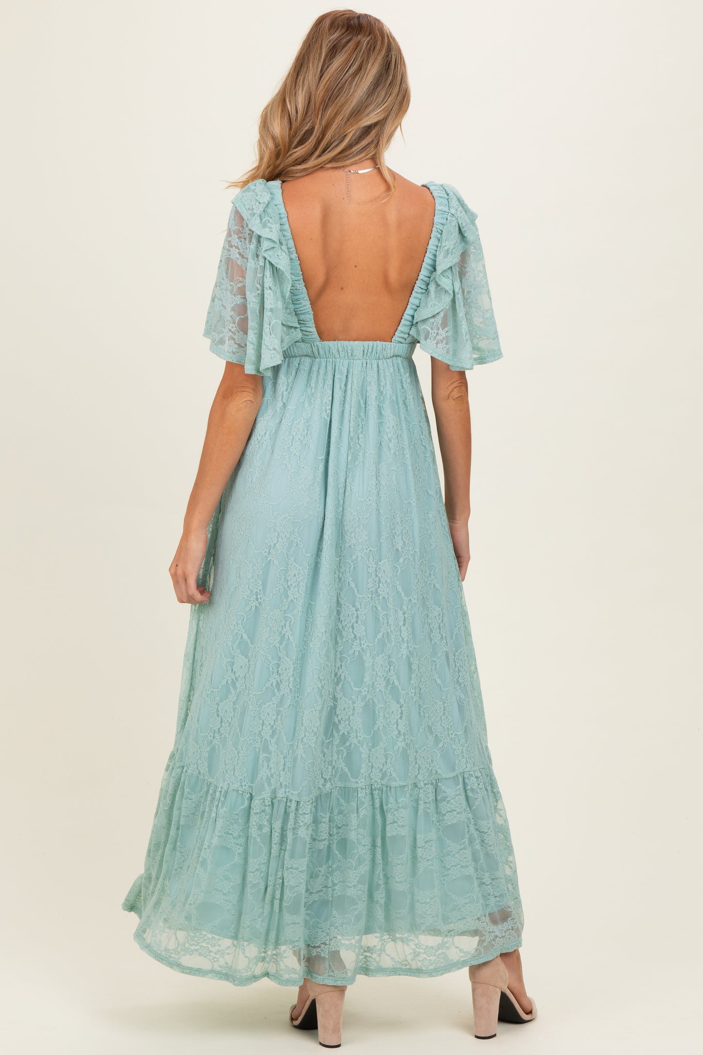 woman wearing a light blue lace maternity maxi dress with flutter sleeves and open back, showing a baby bump