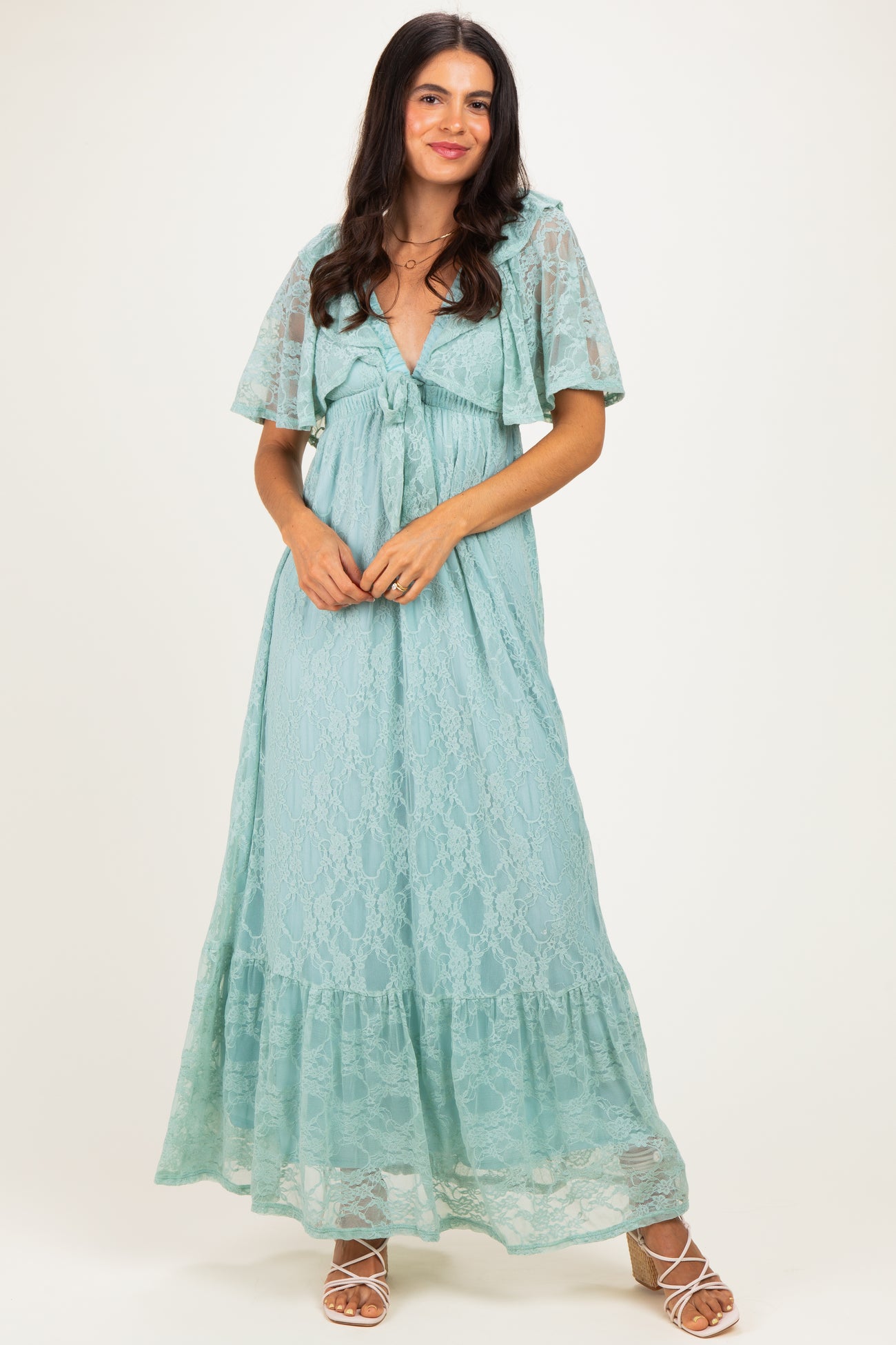 woman wearing a light teal lace maxi dress with flutter sleeves and a tie front detail
