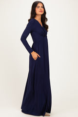 woman wearing a long sleeve navy blue maxi dress with a wrap design and side pockets