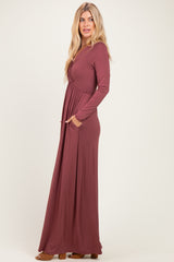 woman wearing a long sleeve burgundy maxi dress with a wrap style and side pockets
