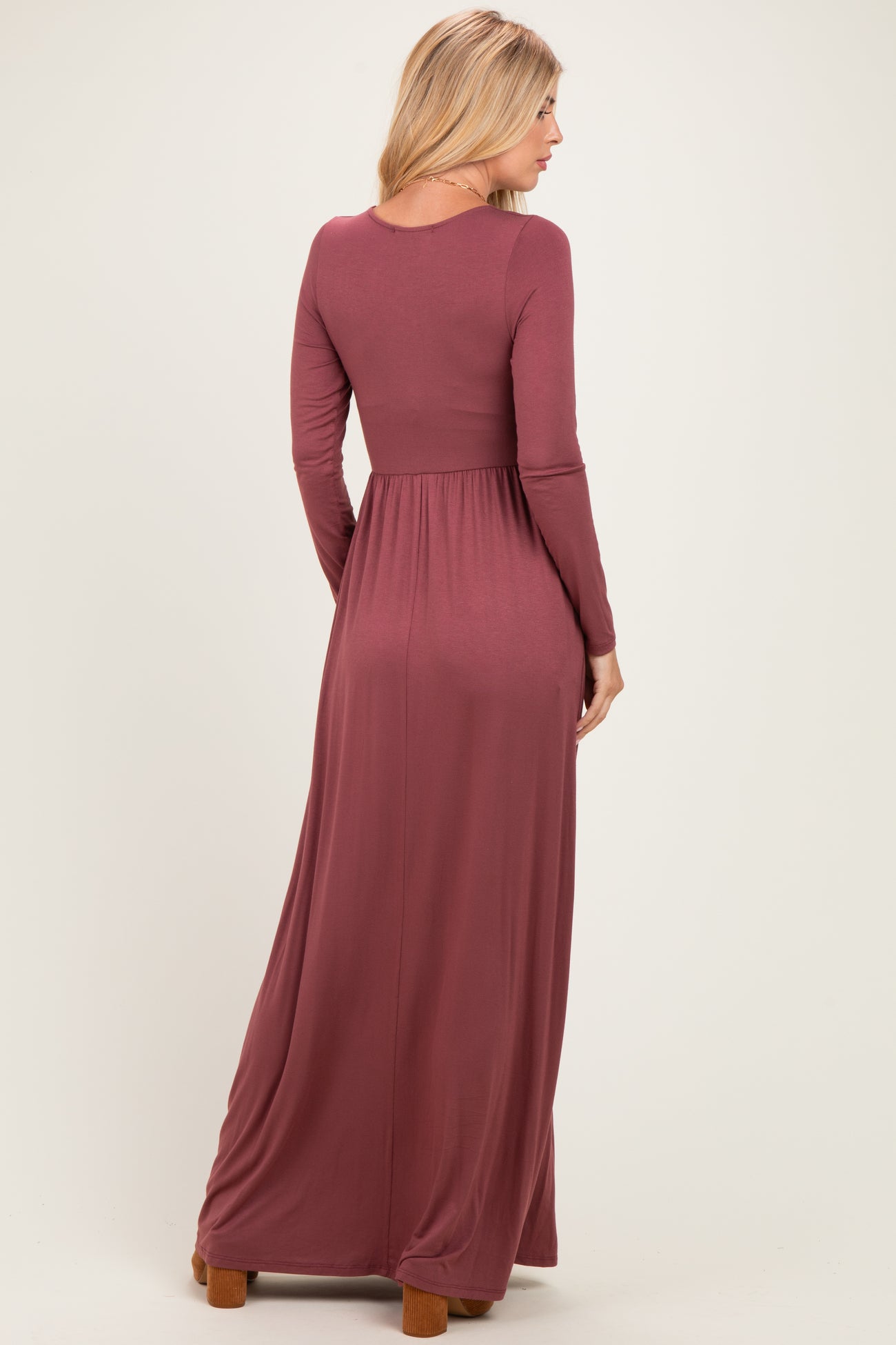 woman wearing a long sleeve burgundy maxi dress with a fitted bodice and flowy skirt, shown from the back