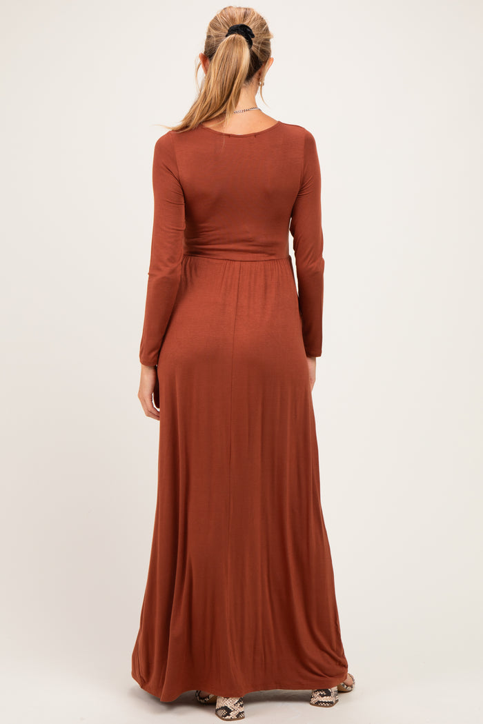 woman wearing a rust long sleeve maternity maxi dress, showing the back view with a flowing skirt