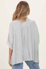 woman wearing a striped maternity top with a flowy back and loose sleeves, styled with light blue jeans