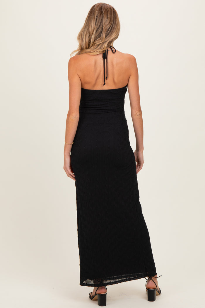 woman wearing a black maternity maxi dress with a halter neck and back ruching, showing her baby bump