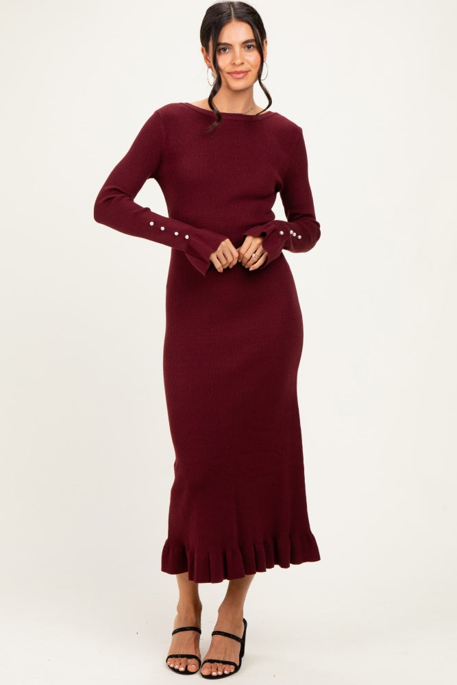 woman wearing a burgundy ribbed knit long sleeve dress with ruffle hem and button detail on sleeves