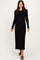 woman wearing a black ribbed long sleeve maxi dress with a fitted silhouette and slit detail at the hem