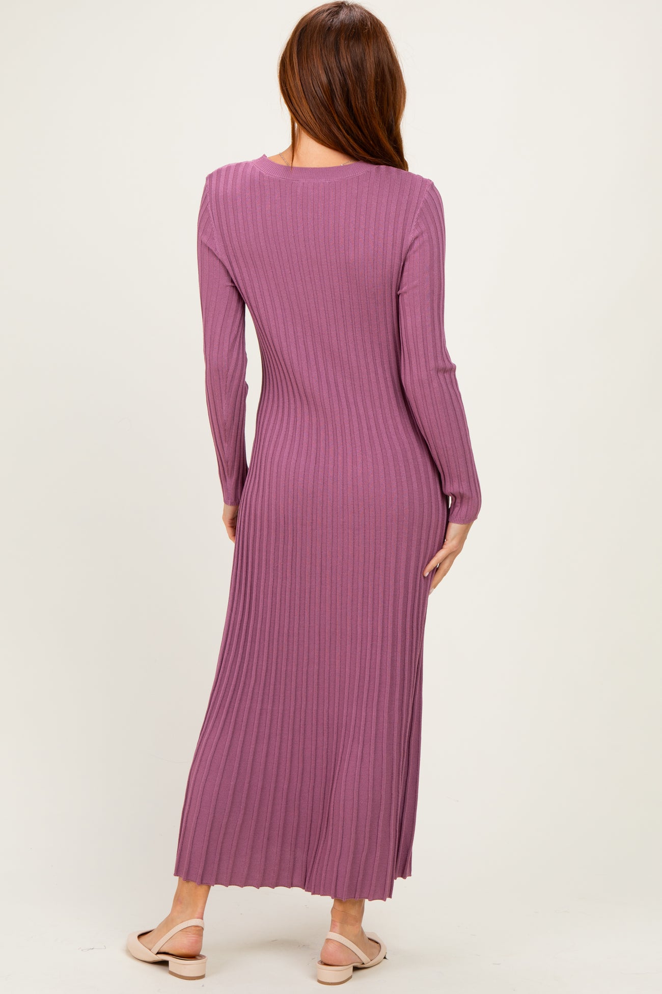 woman wearing a mauve long sleeve ribbed maxi dress, showcasing a fitted silhouette and flowy hem from the back