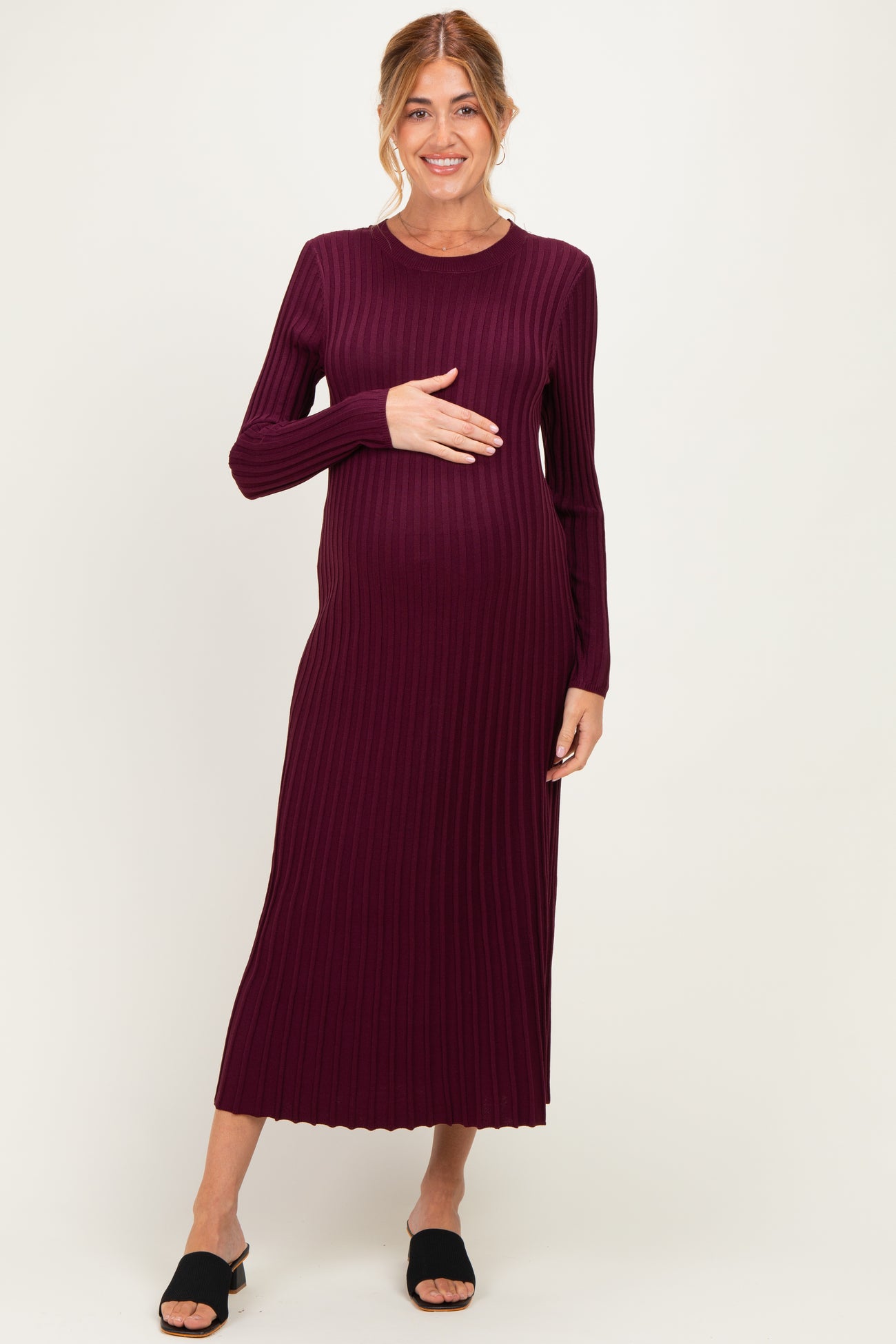 woman wearing a burgundy long sleeve ribbed maternity dress and holding her baby bump
