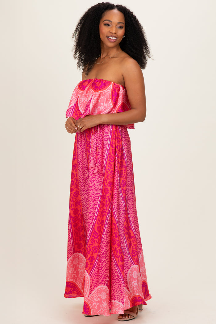 woman wearing a pink strapless maxi dress with a layered ruffle top and bold print patterns