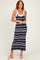 woman wearing a navy and gray striped maxi dress with a white neckline and smiling while standing
